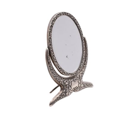 An Edward VII silver oval swing frame easel dressing table mirror, Chester 1902 with embossed flowerhead and foliate scroll d