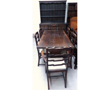 An oak reproduction dining suite, near matching and comprising plank top refectory table, 6 ladder back chairs and full heigh