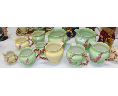 A Carltonware graduating set of 5 jugs, green leaf and hollyhock pattern; 2 similar jugs; a set of 3 yellow hollyhock jugs (2