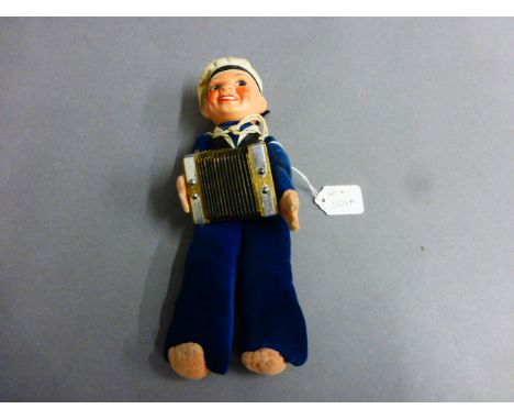 Original clockwork souvenir sailor playing a squeeze box with painted composition head and velour sailors costume. The hat pr