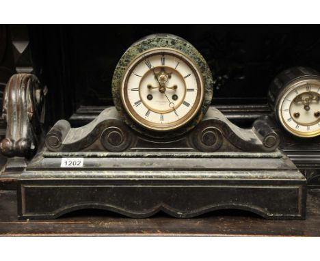 A black slate and marble mantel clock with an enamel dial and visible escapement. The dial with the inscription Frisch & Schi