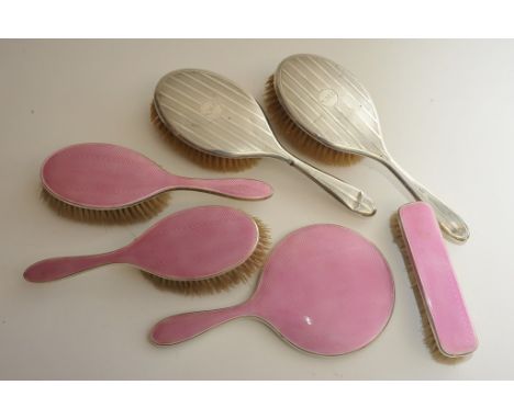 A silver and pink enamel backed hairbrush set with one other pair of silver brushes
