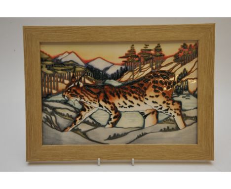 A framed porcelain panel trial tile with tube line decoration by Moorcroft depicting a Lynx in a mountainous landscape