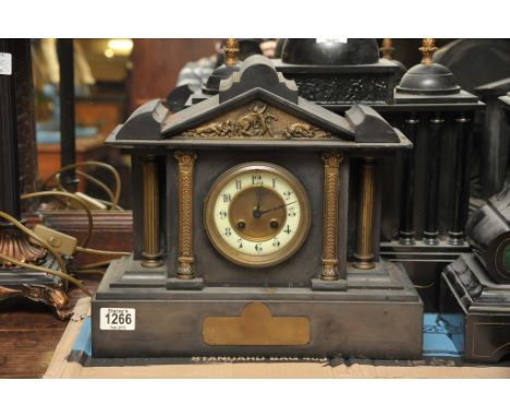 A Victorian black slate mantel clock with an enamel chapter ring flanked by brass pillars 
