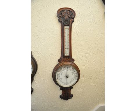 A carved oak android wall barometer 
