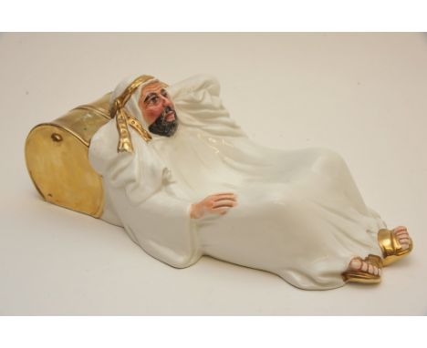 A ceramic dish modelled in the form of a reclining sheikh in white robes resting upon a gilt barrel by Antonio Zen