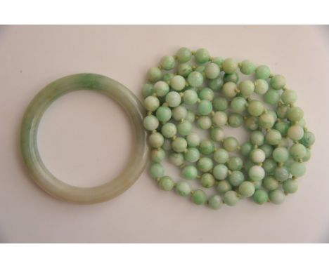 A solid Chinese jade bangle together with a jade necklace