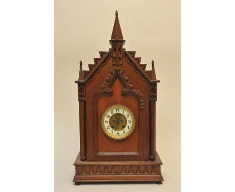 A walnut cased mantle clock of ecclesiastical style with enamel chapter ring