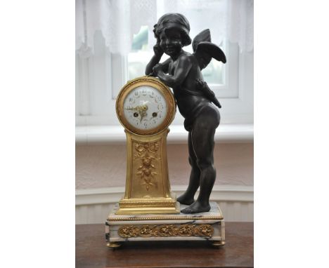 A French early 20th bronzed and gilt metal mantel clock the enamel dial decorated with foliate swags and flanked by a winged 