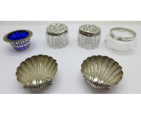 A pair of Victorian silver shell shaped salts, one other silver salt with liner, a silver rimmed salt and two silver topped g