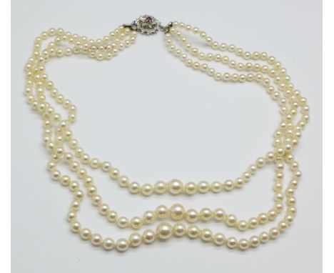 A three strand pearl necklace on an 18ct white gold clasp set with pink stone