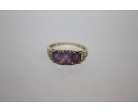 A HALLMARKED 9K GOLD THREE STONE AMETHYST DRESS RING WITH DIAMOND CHIPS TO THE SHOULDERS APPROX WEIGHT - 2.6G 