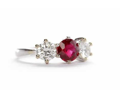 EIGHTEEN CARAT WHITE GOLD RUBY AND DIAMOND THREE STONE RINGthe central round ruby of approximately 1.18 carats flanked by two