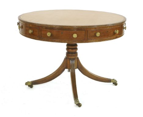 A George III mahogany drum table,the leather inset top over real and dummy frieze drawers, a turned column and four reeded, o