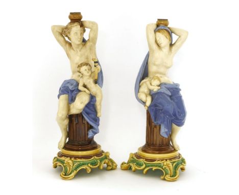 Two Minton majolica table lamp stands,date codes for 1864 and 1865, each modelled as night and day, seated on column plinths,