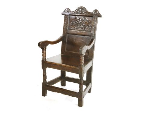 An oak wainscot chair,17th century, with a shaped back, feather carved frame, flanking a carved panel and initialled twice 'M