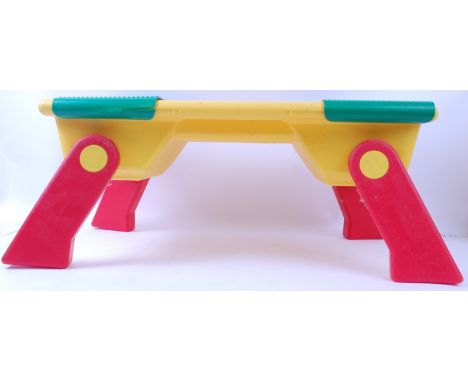 LEGO; A vintage Lego Play Table in red and yellow, with fold out legs. Two sliding covered compartments to the top, both cont