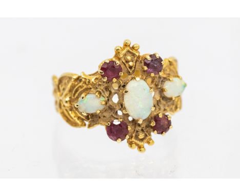 An opal and ruby set 14ct gold ring, comprising oval opals and round mixed cut garnets, claw set to a textured mount, width a