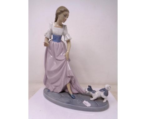 A Nao figure of a girl with puppy tugging dress 