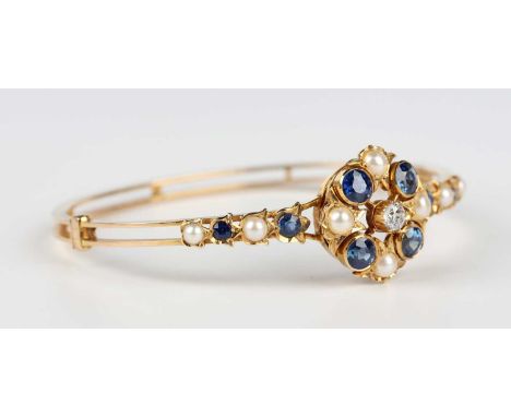 A gold, diamond, sapphire and half-pearl oval hinged bangle, early 20th century, the central cluster mounted with a cushion c