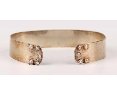 A 9ct white gold bangle, each terminal mounted with five cushion cut diamonds, London 1987, weight 21.4g, inside width  6.8cm
