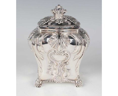 A late Victorian silver tea caddy of rectangular bombé form with hinged lid and stylized scallop shell finial, the body embos