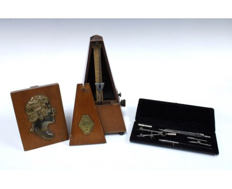 Metronome, 21cm, together with a cased protractor set and a metal bust silhouette on a wooden block (3)