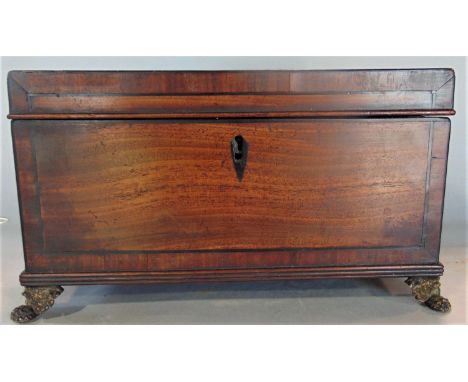 A Georgian mahogany and rosewood cross banded tea caddy with twin brass lion head handles and fancy paw feet, the hinged lid 
