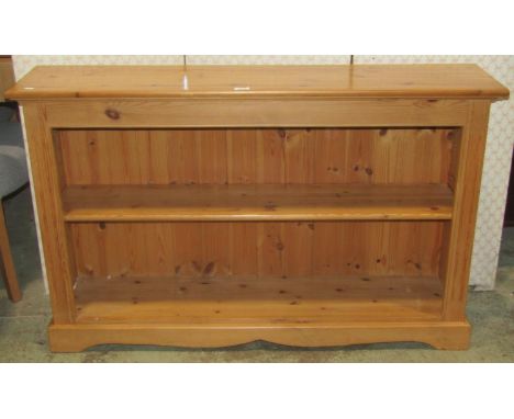 A dwarf stripped pine freestanding bookcase with single adjustable shelf, 127 cm wide x 30 cm deep x 79 cm high, together wit