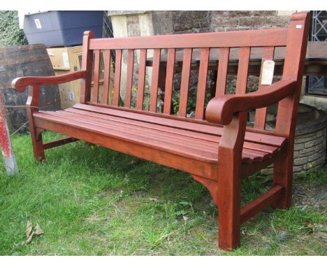 A substantial teak three seat garden or park bench with slatted seat and back, open scrolled arms and stained finish, stamped