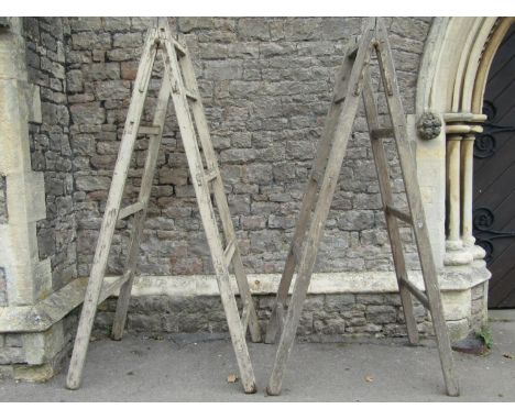 A pair of substantial vintage A framed folding trestles, 220cm high, together with three further pine framed step ladders of 