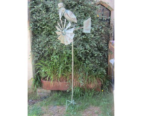 A contemporary light steel novelty garden wind generator, the finial in the form of a bird wearing a hat and circular rim gla