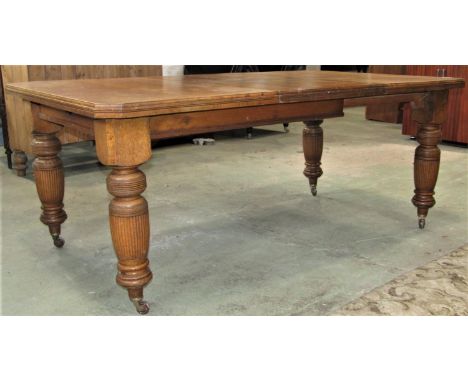An Edwardian medium to light oak wind out extending dining table with canted corners, moulded outline and single additional l