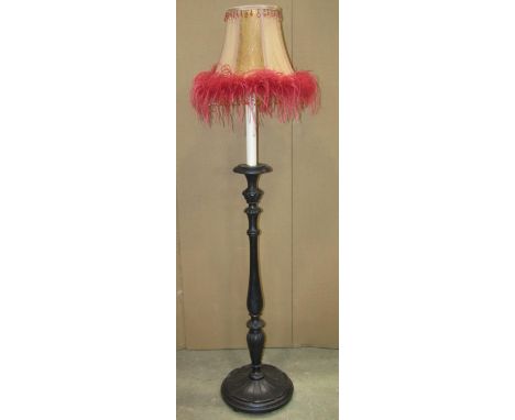An ebonised wooden standard lamp in the form of a candle stand with turned stem, petal collar and moulded disk shaped platfor