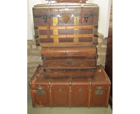 Three vintage travelling trunks including a domed example with lathe overlay, a further tin trunk with simulated graining, a 
