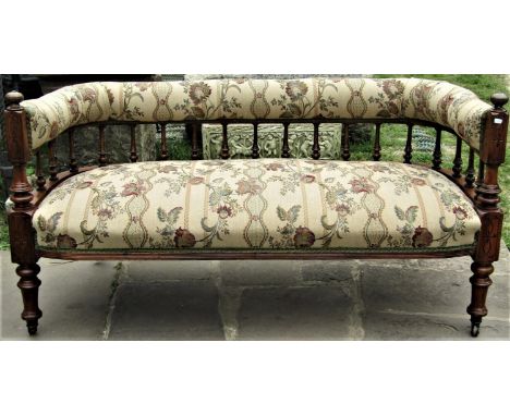 A Victorian walnut sofa, the horseshoe shaped back raised on turned and tapering finials with carved and turned supports, re-