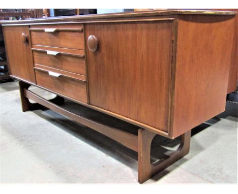 A retro long and low teak sideboard partially enclosed by a pair of doors with large button handles flanking a tower of three