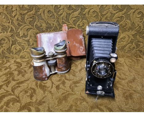 Kodak Model D Junior folding camera and a pair of brass and leather binoculars.