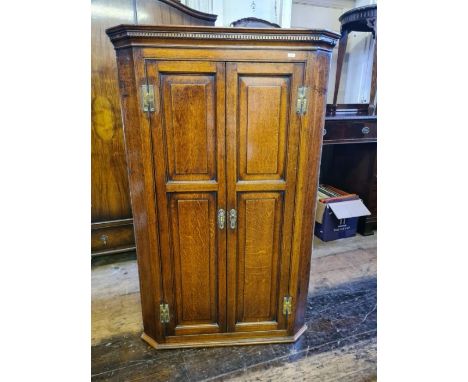 Tall Georgian oak 4 panel 2 door corner cupboard with shaped internal shelves and dentil pediment.  133cm tall.