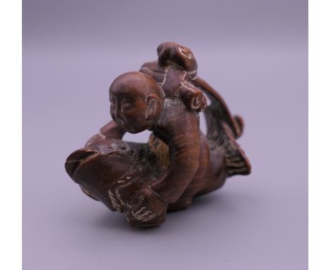 A wooden netsuke formed as a boy and fish. 4.5 cm x 4 cm.