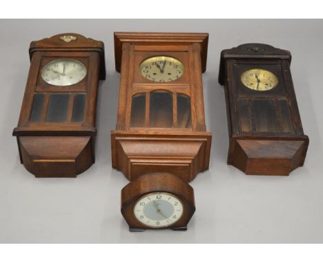 Three late 19th/early 20th century oak wall clocks and a mantle clock. The largest 64 cm high.