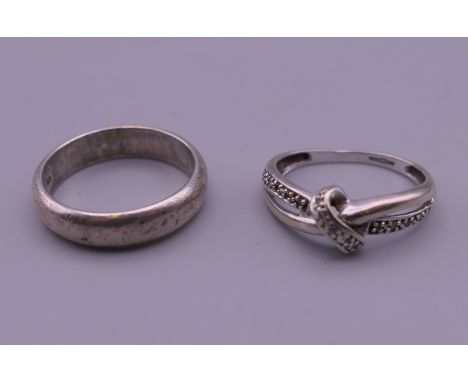 A white gold cross over ring and a silver ring. The former ring size L/M, the latter ring size P.