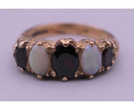 An unmarked gold, probably 9 ct gold, opal and garnet ring. Ring size P/Q