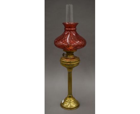 A Victorian brass oil lamp with ruby glass shade. 77 cm high overall.