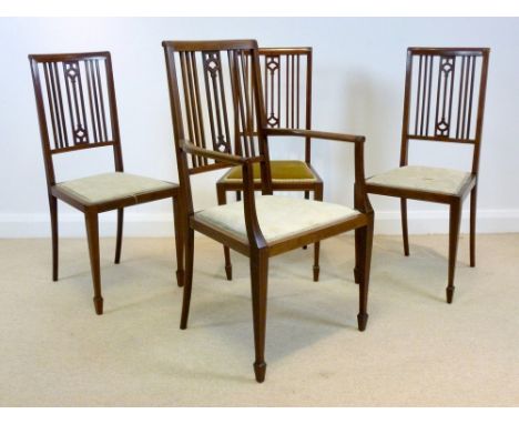 A set of four Edwardian mahogany and inlaid dining chairs, including one carver, with pierced stick backs, beige upholstered 