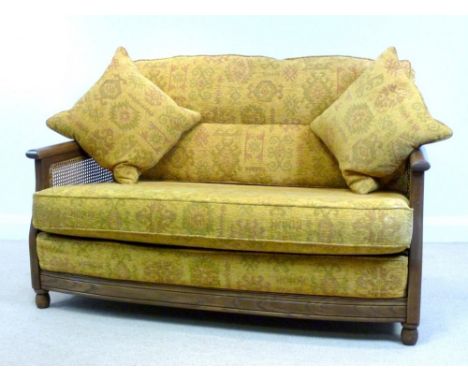 A modern Ercol dark stained elm two seater bergere settee, with mustard coloured upholstery, 140 by 90 by 59cm high.