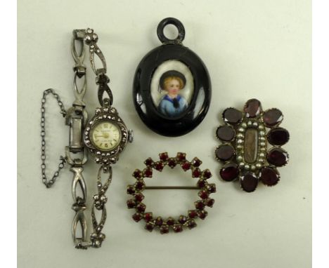 A Victorian mourning brooch set with plaited hair, surrounded by seed pearls and ten garnets, an Ingersoll 1930s cocktail wat