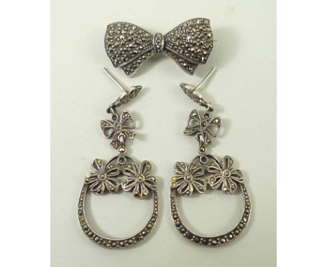 A pair of silver and marcasite horse shoe and flower earrings, and a bow tie brooch. (3)