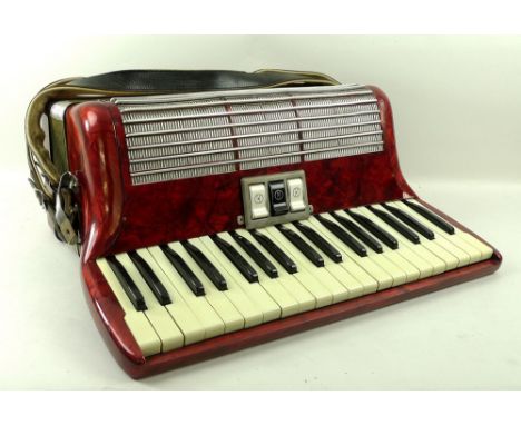 A Hohner piano accordion, finished in red, 50 by 41 by 22cm, cased.