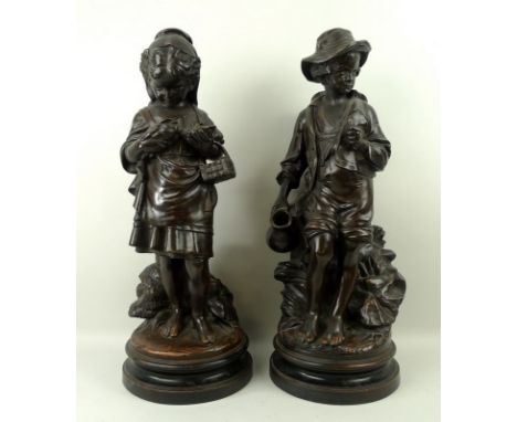 A pair of German terracotta figures, late 19th century, of a standing boy holding a flagon against a rock formation, and a gi